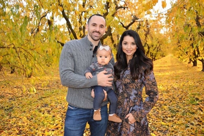 Pete, his wife, and their daughter standing in autumn foliage 